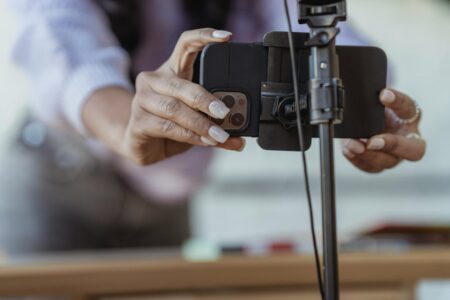 Person holding smartphone recording live video stream in professional lighting setup