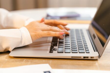 Person typing on laptop computer for creative writing and digital publishing