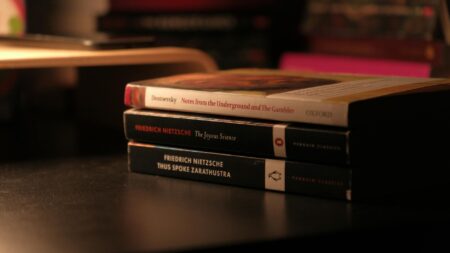 Stack of books arranged on wooden table with reading materials