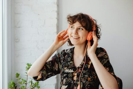 Woman wearing headphones while working on laptop in home office environment