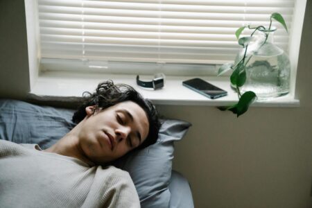Modern wearable sleep tracking device on bedside table next to sleeping person