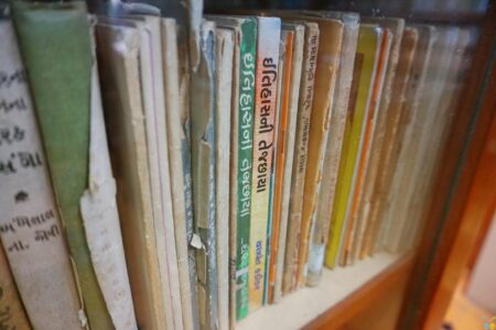 Rows of old hardcover books on a wooden library shelf