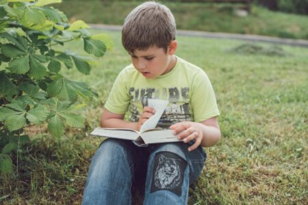 A young child sitting alone reading a picture book indoors