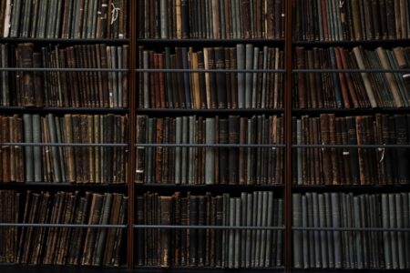 Lit Hub Daily: June 26, 2026 Worn historical books stacked in a library archive, spines facing outward