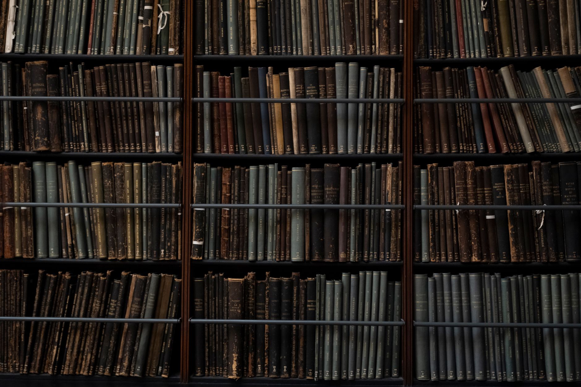 Worn historical books stacked in a library archive, spines facing outward