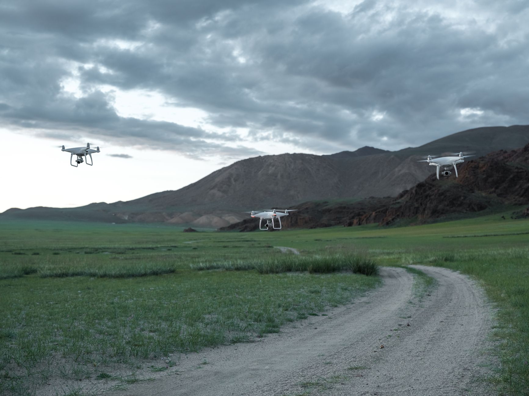 A small military drone hovering over an open field during training