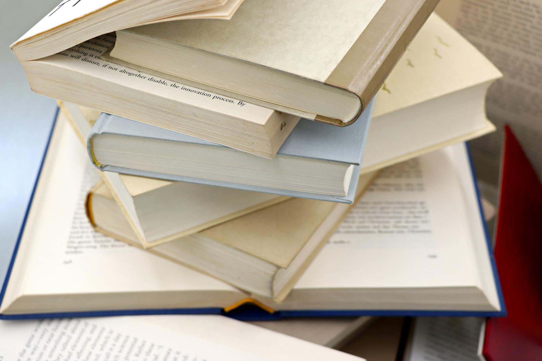 A stack of open novels and paperbacks on a wooden table