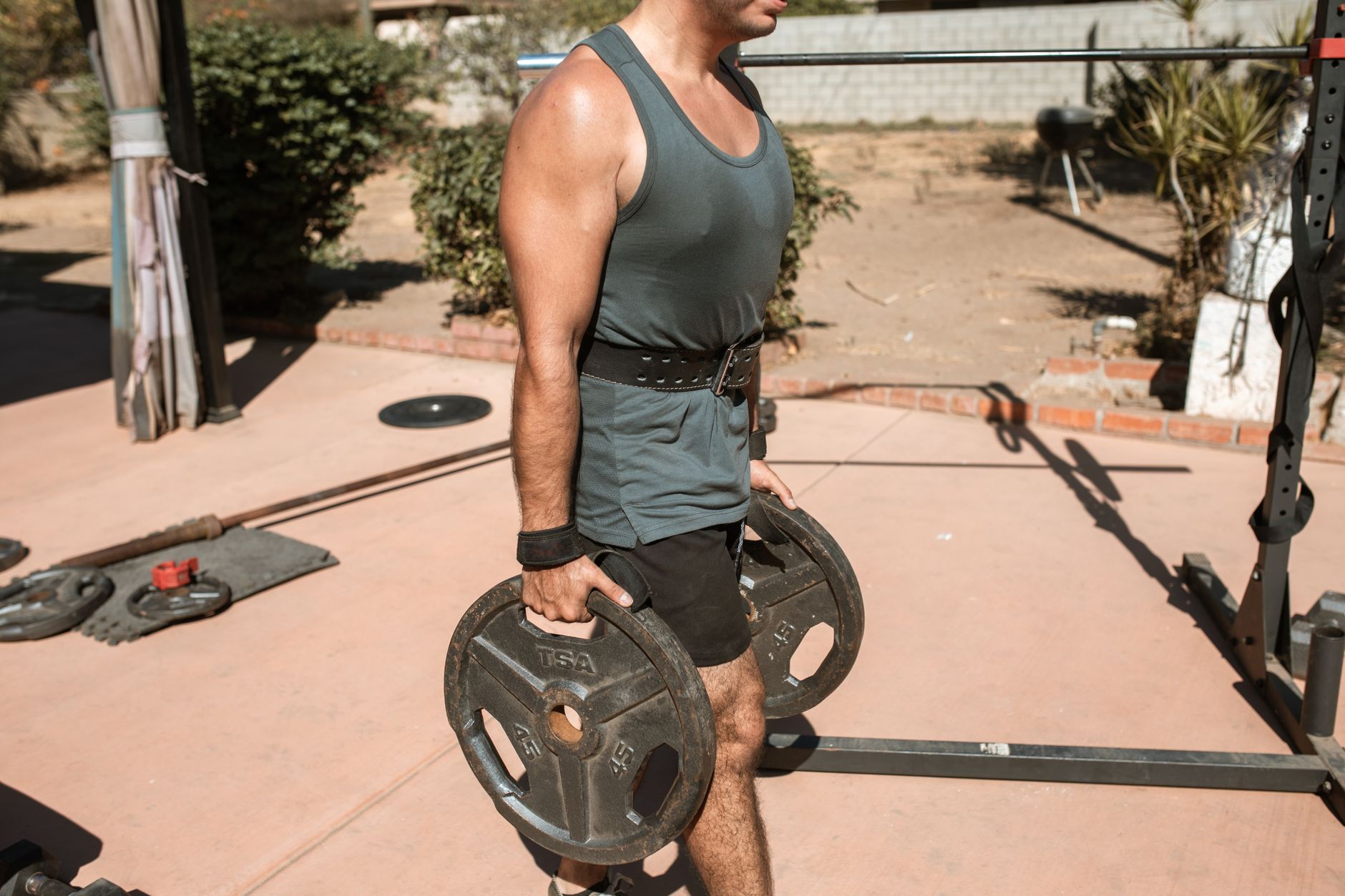 Person carrying heavy dumbbells in each hand across a gym floor