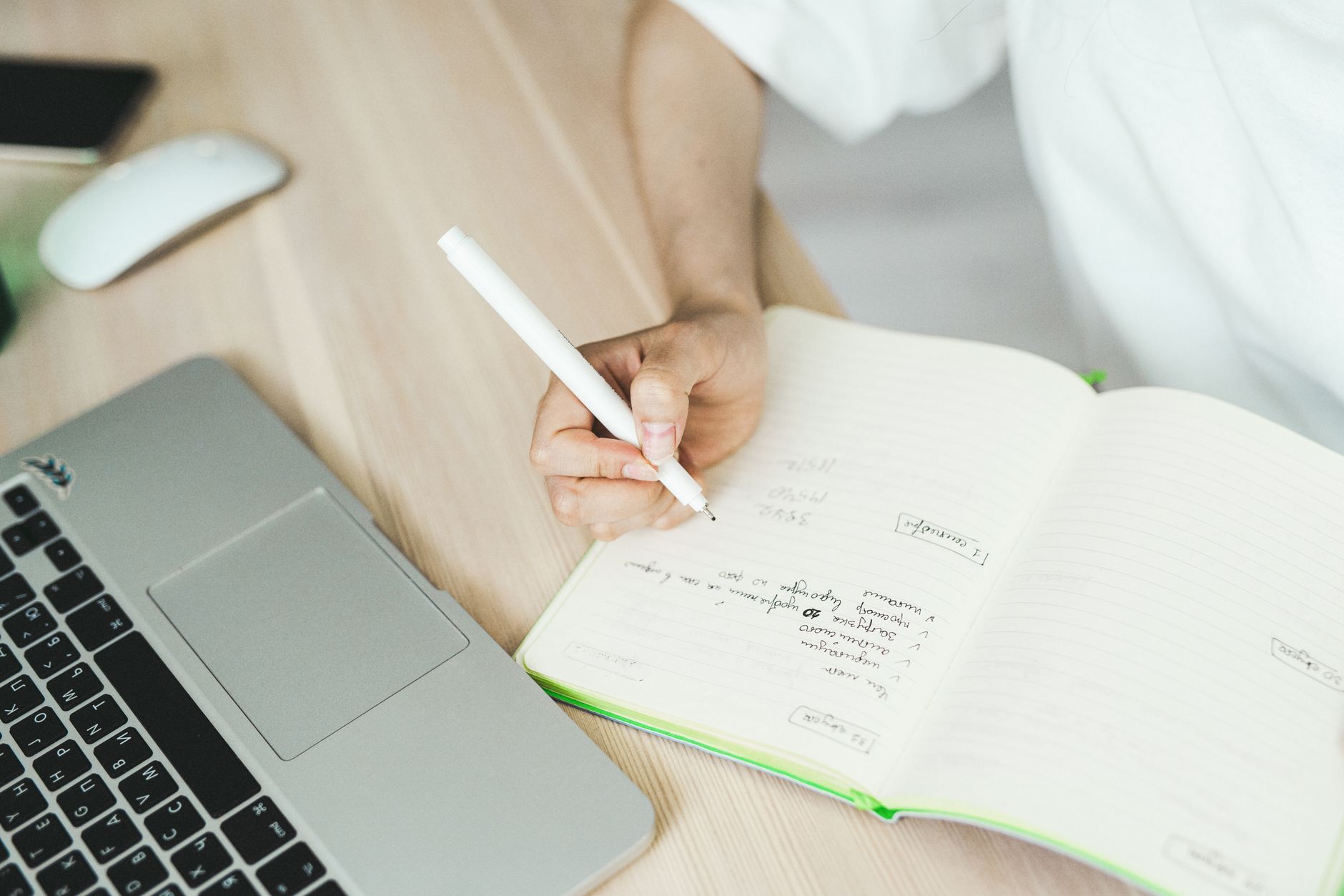 A writer's open notebook on a wooden desk with a pen resting across the page