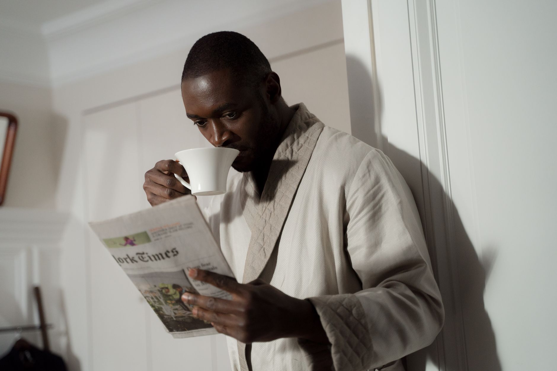 Person reading a broadsheet newspaper indoors under warm light