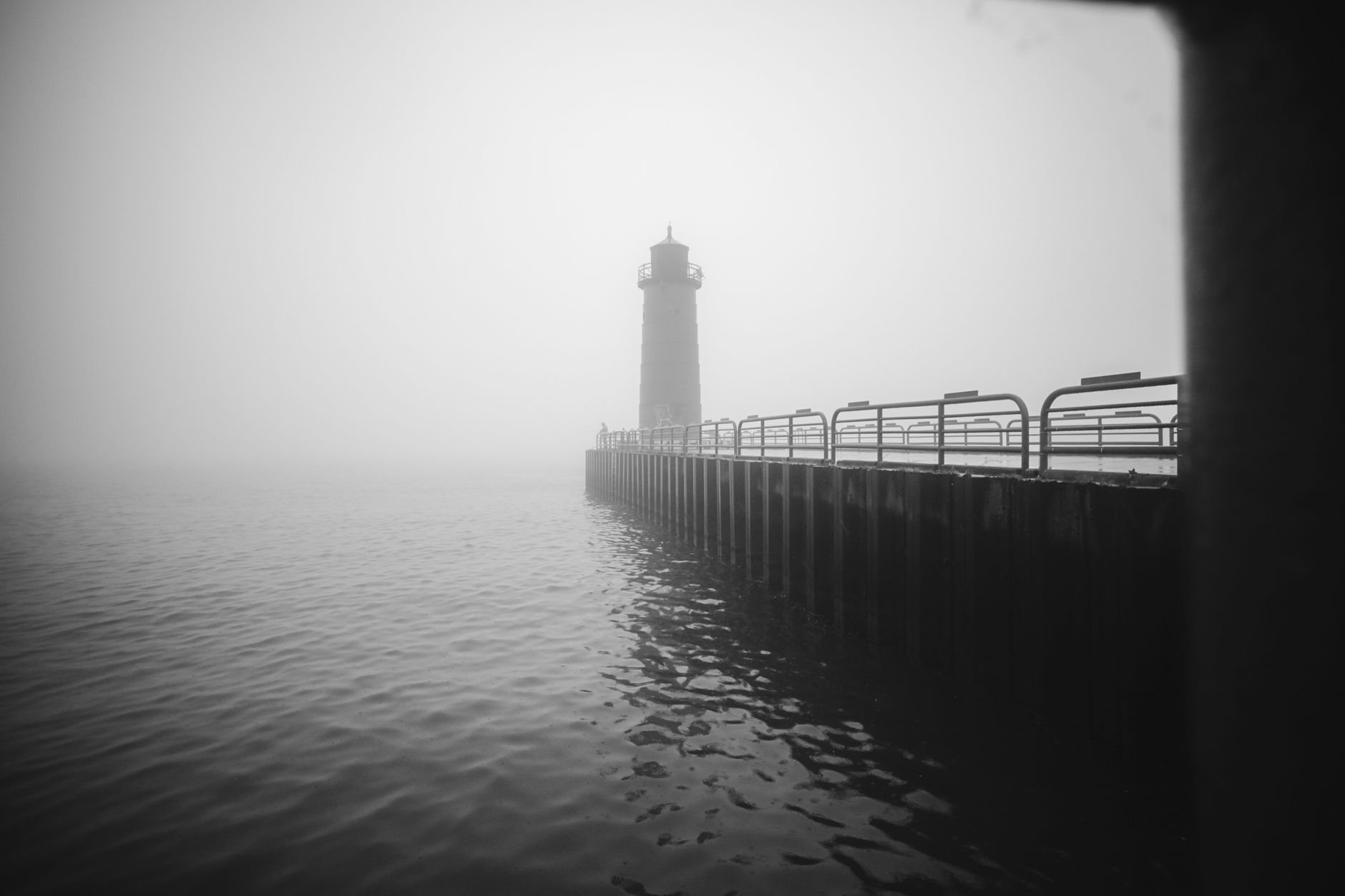 A solitary lighthouse standing in coastal fog at dusk