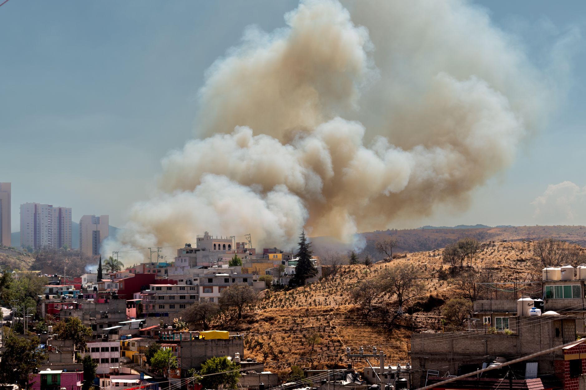 Smoke rising near a residential neighborhood from industrial equipment