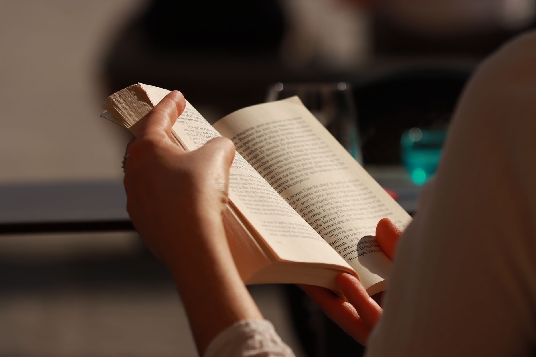 A person reading a paperback book in a quiet indoor setting