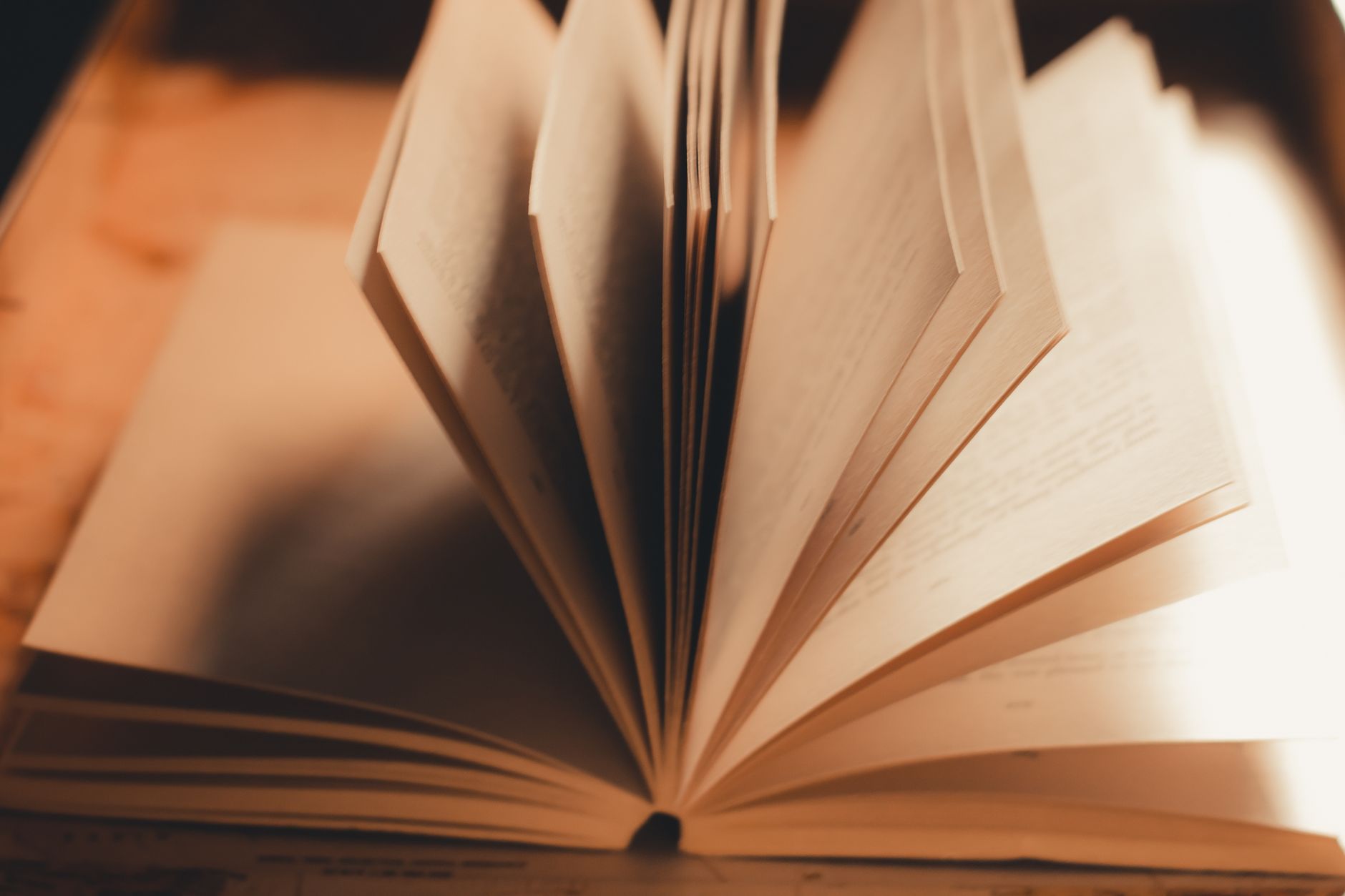 A handwritten reading list on paper beside a stack of novels