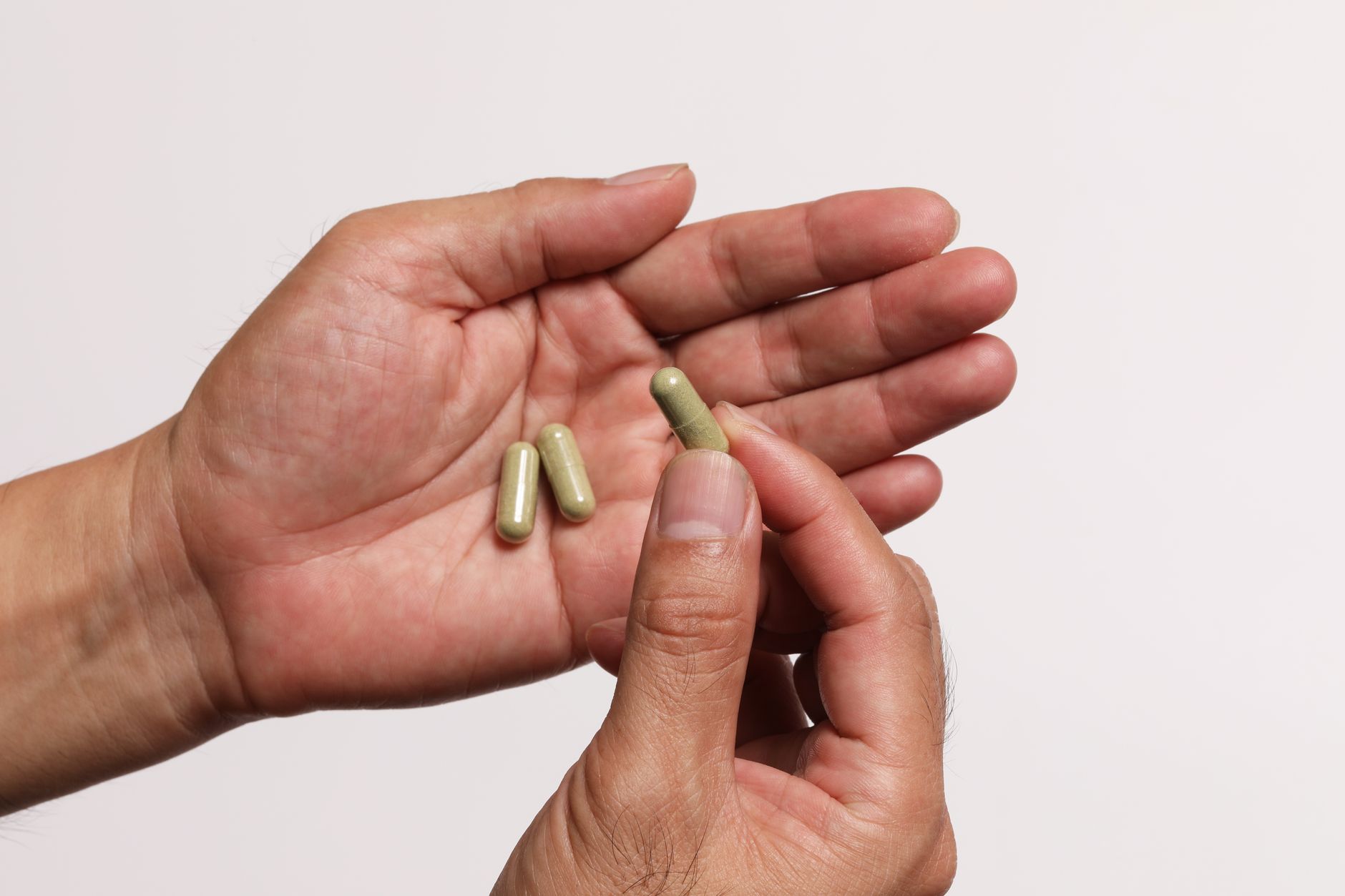 Man holding magnesium supplement capsules above an open bottle