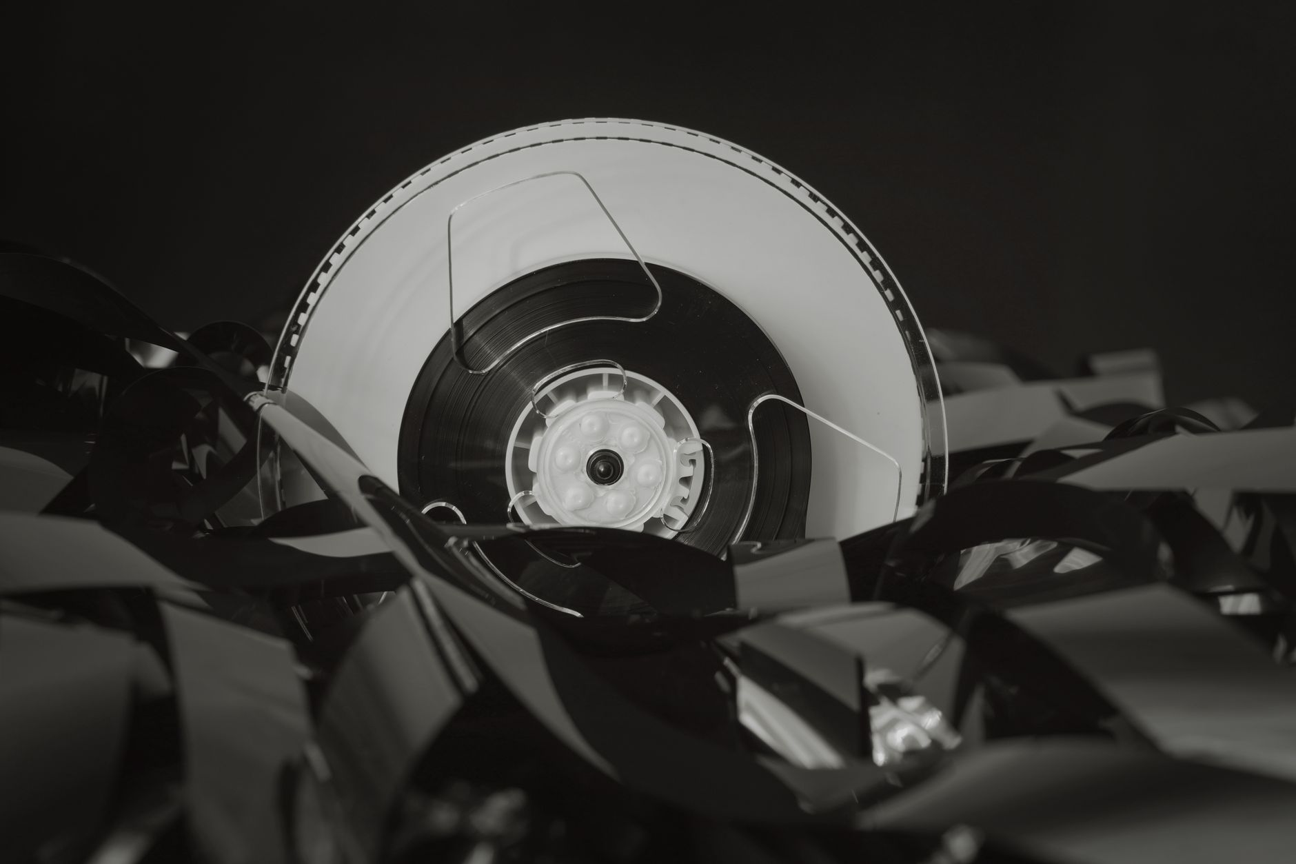 A stack of literary novels next to a vintage film reel on a wooden surface