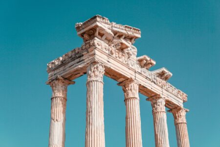 Weathered stone columns at ancient Greek archaeological site under clear sky
