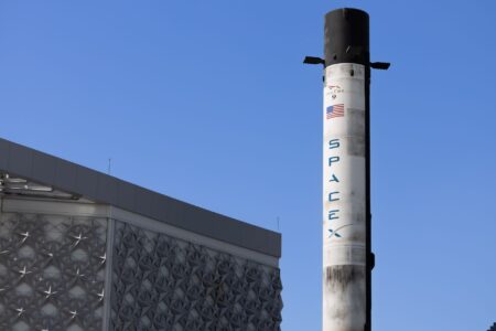 Large rocket standing on a launch pad at dusk with support structures visible