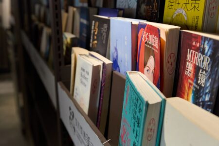 A bookseller arranging titles on a wooden shelf in an independent bookstore