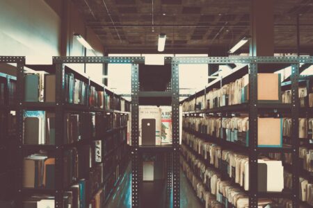 Rows of aged books on wooden library shelves with warm light
