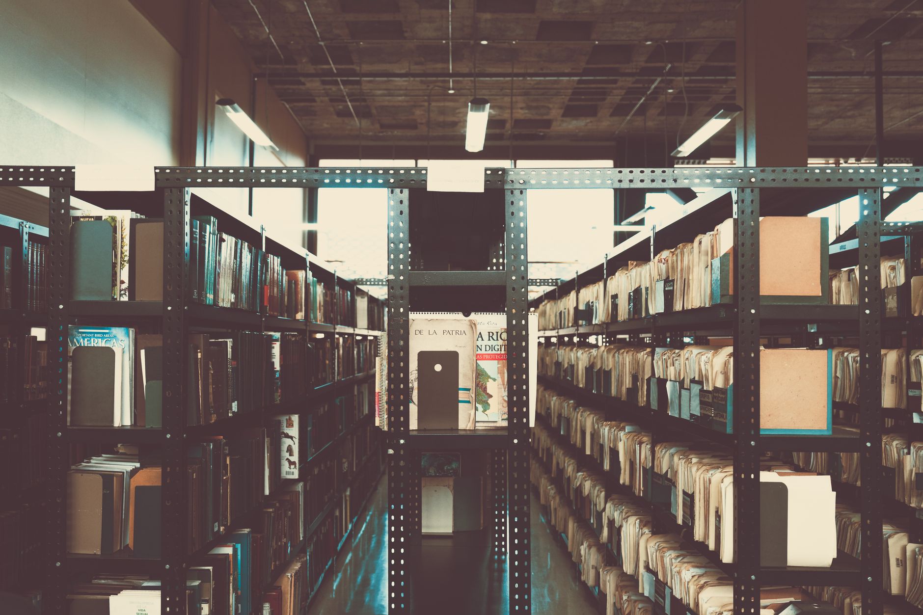 Rows of aged books on wooden library shelves with warm light