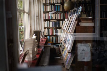 Rows of weathered books on wooden shelves in a dim independent bookshop