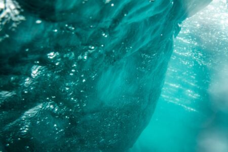 Dark blue ocean water seen from below the surface, light filtering down from above
