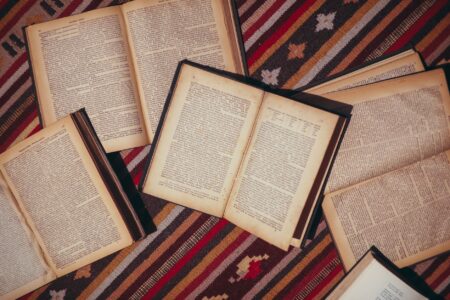 Stack of open books on a wooden library table with warm lighting