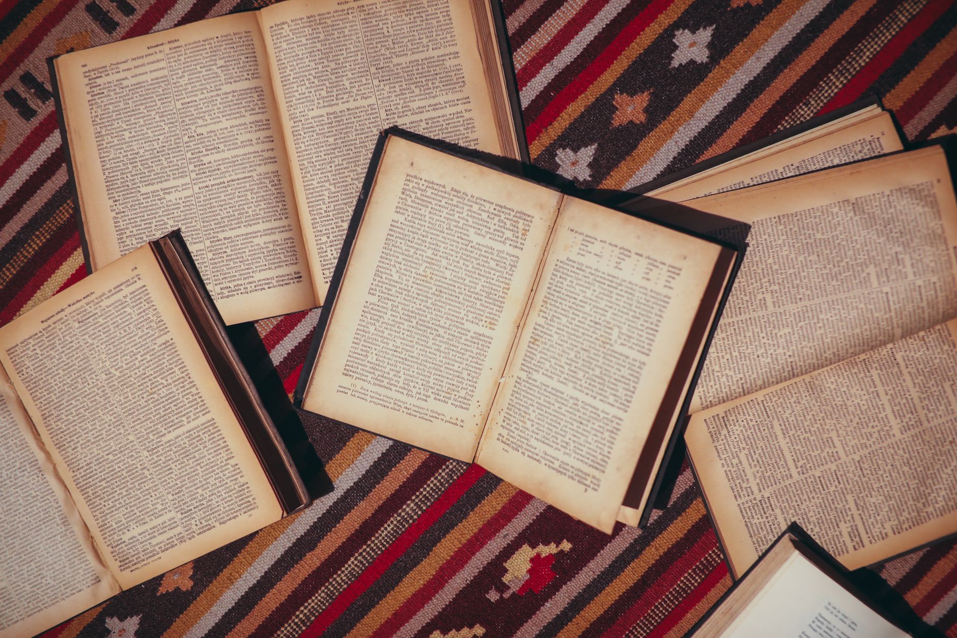 Stack of open books on a wooden library table with warm lighting