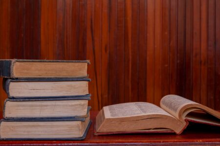A stack of open books spread across a wooden table, pages fanned out