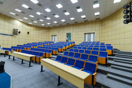 Empty university lecture hall with rows of wooden seats and a front chalkboard