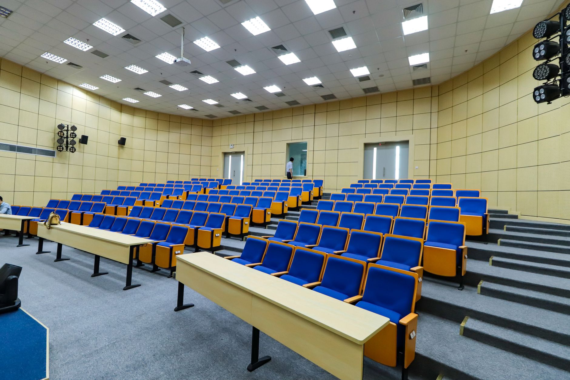 Empty university lecture hall with rows of wooden seats and a front chalkboard