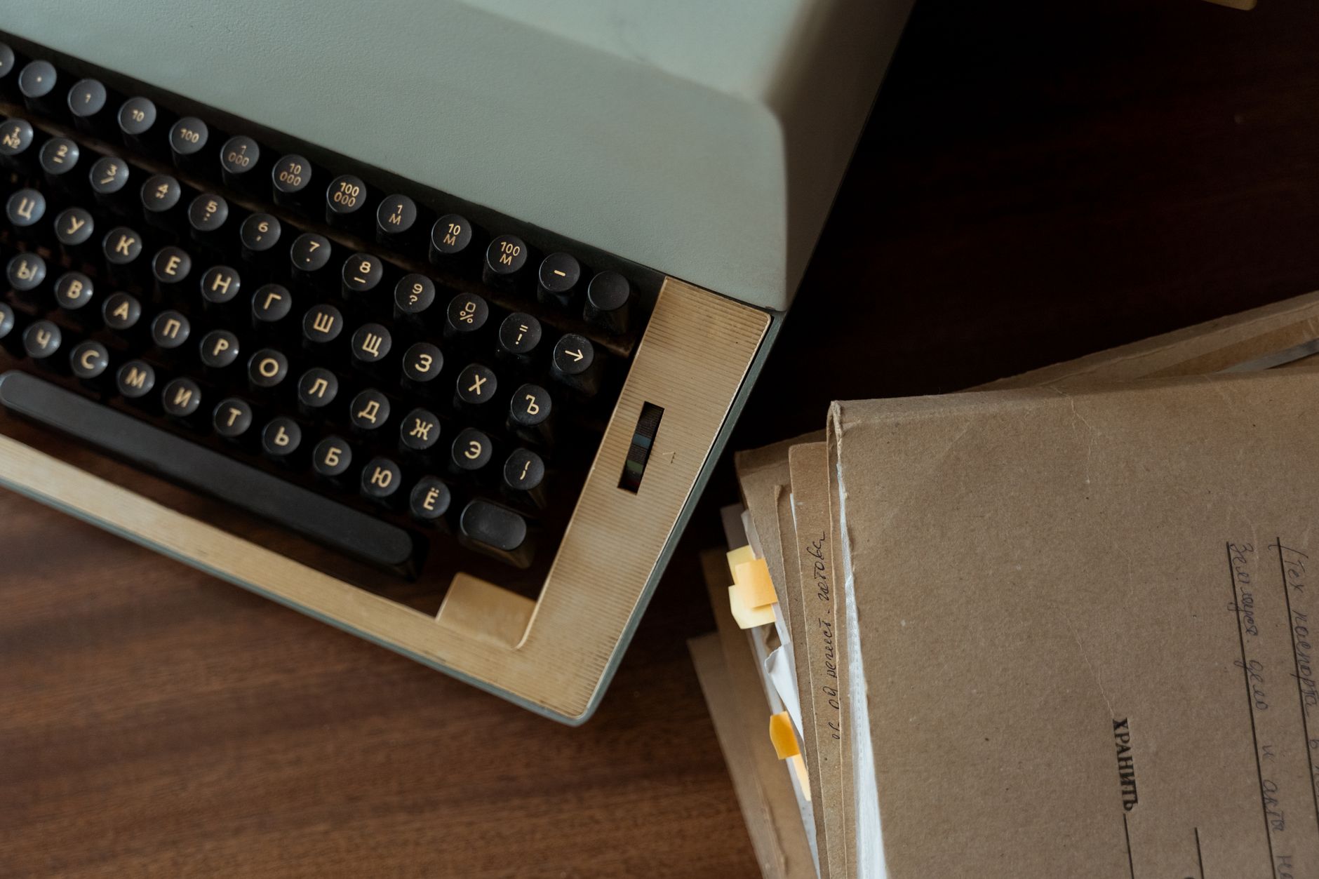 A vintage typewriter on a wooden writing desk with papers