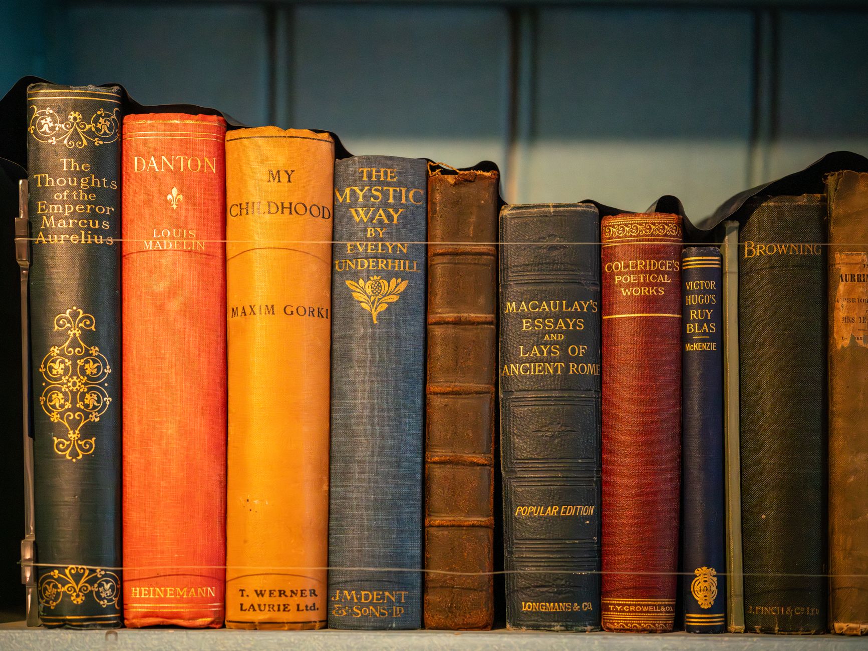 A stack of worn hardcover books on a reading table in soft light