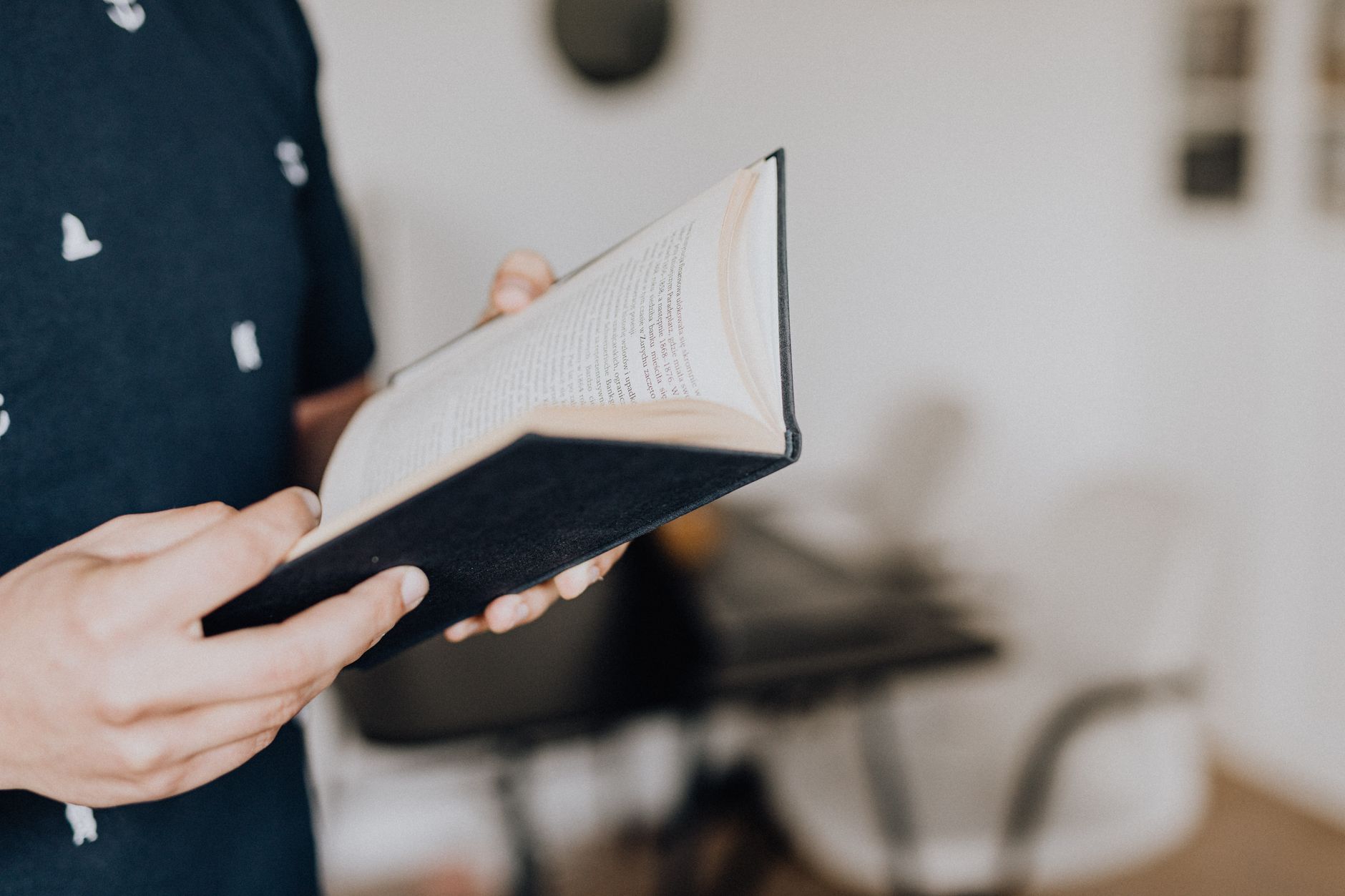 A worn paperback book lying open on a wooden table in natural light