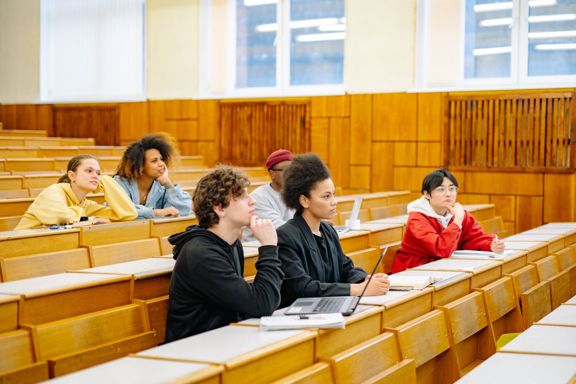 Empty university lecture hall with tiered seating and a chalkboard at the front