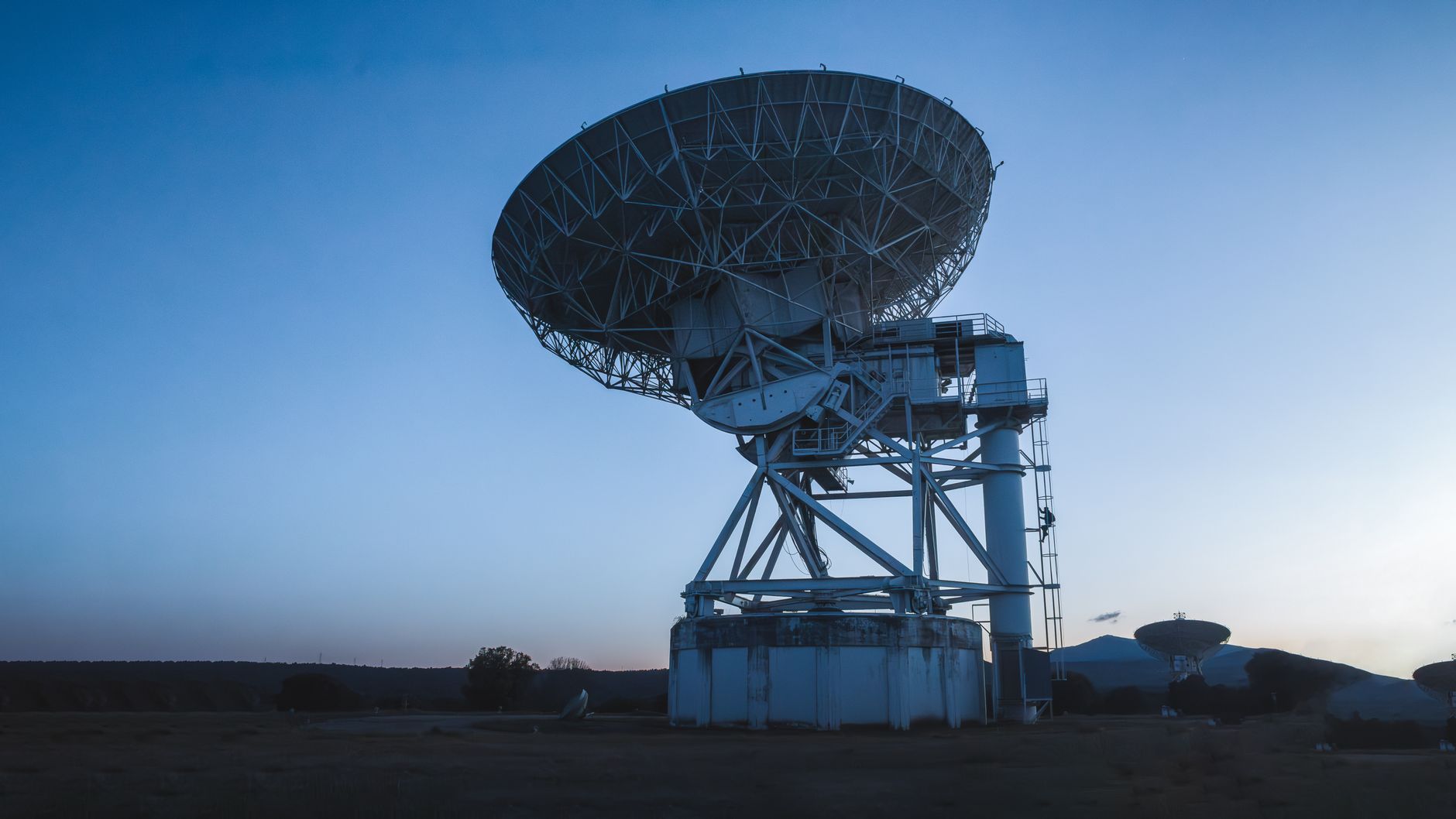 Large satellite dish antenna array pointed toward the sky at a communications complex