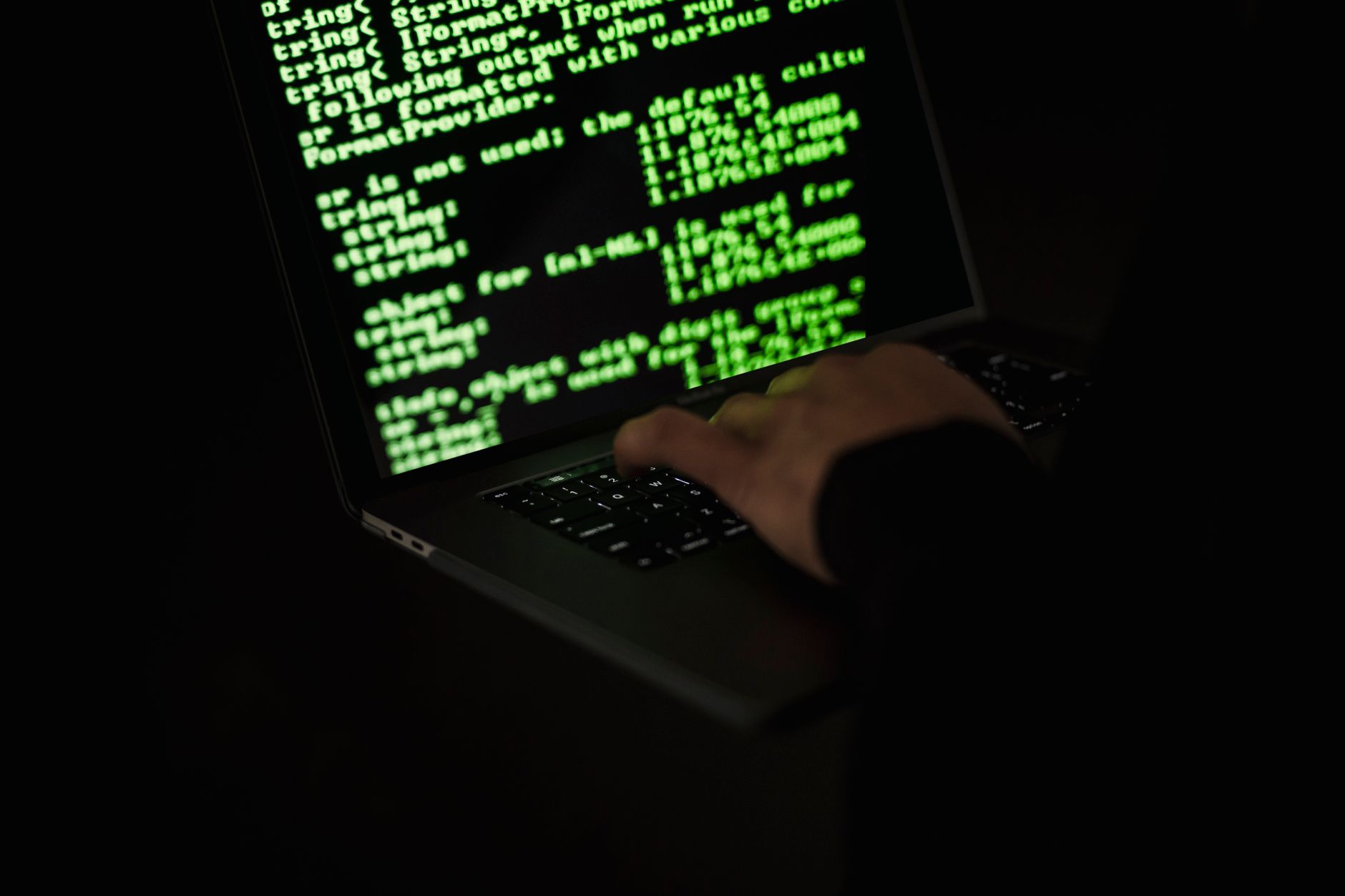 Person working at a glowing computer screen in a dark room