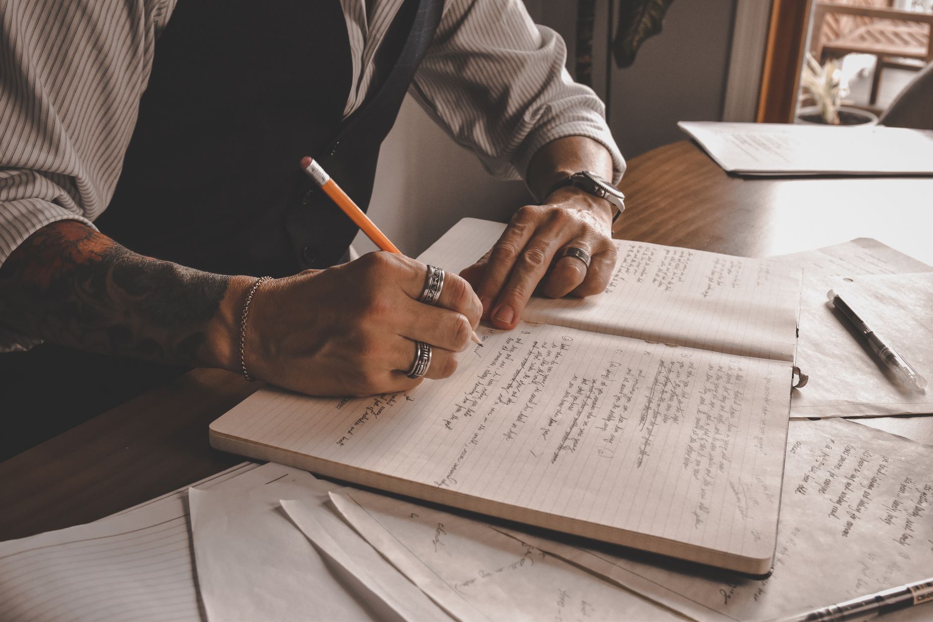 A writer at a wooden desk surrounded by books and notes