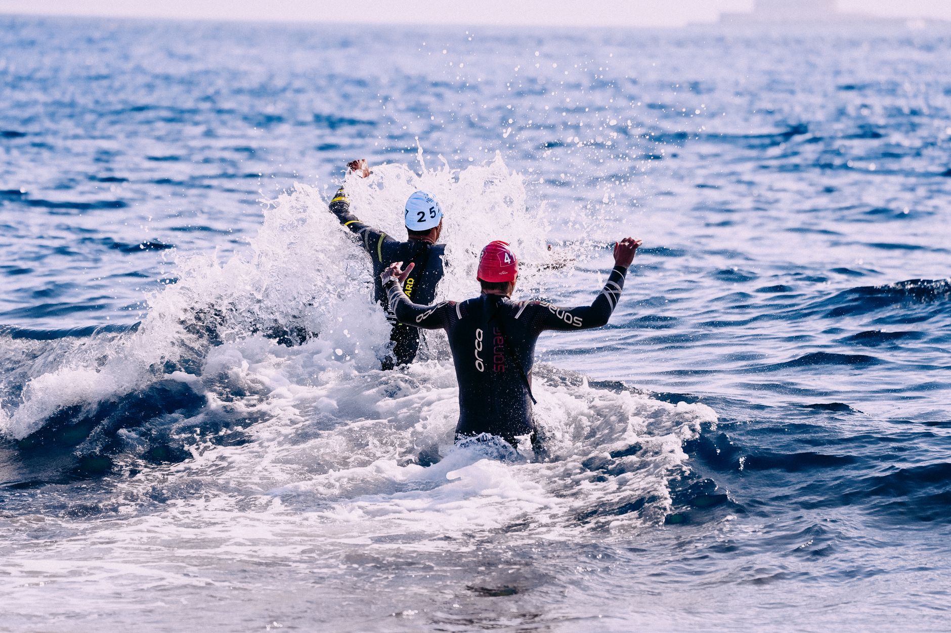 A lone swimmer moving through calm open water, light reflecting on the surface