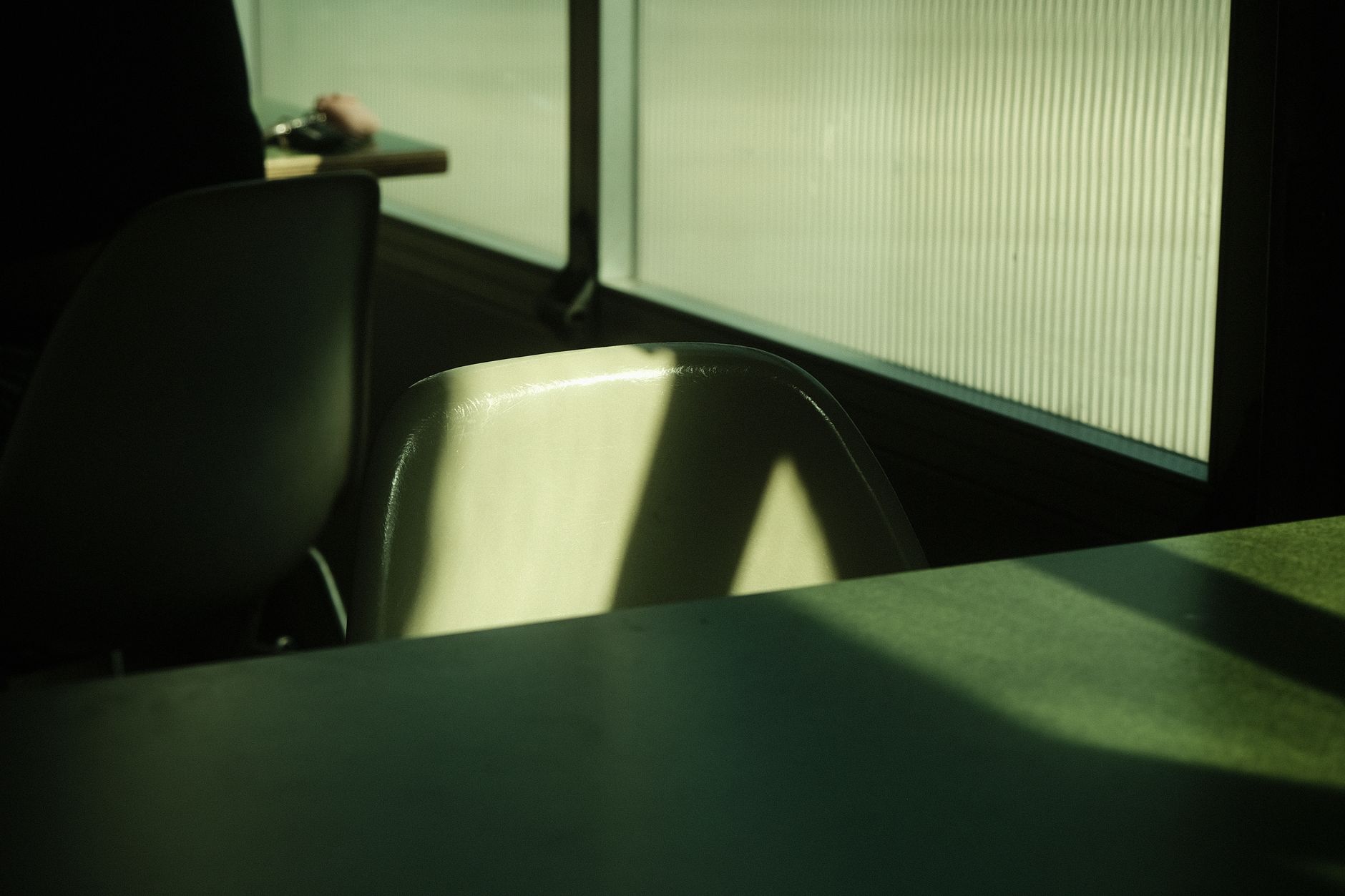An empty wooden chair beside a sunlit window suggesting absence and memory