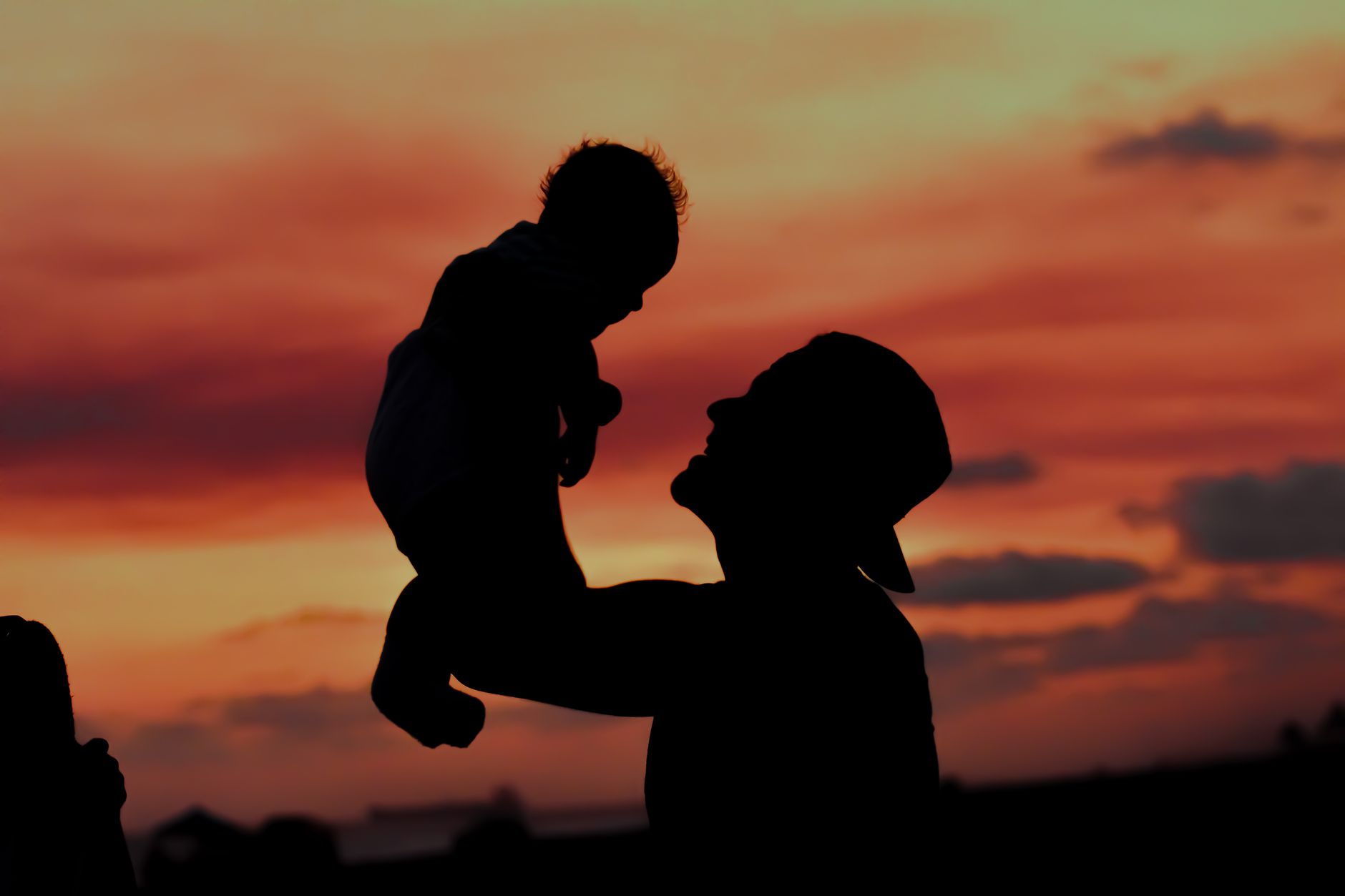 Silhouette of an adult and child standing together at dusk