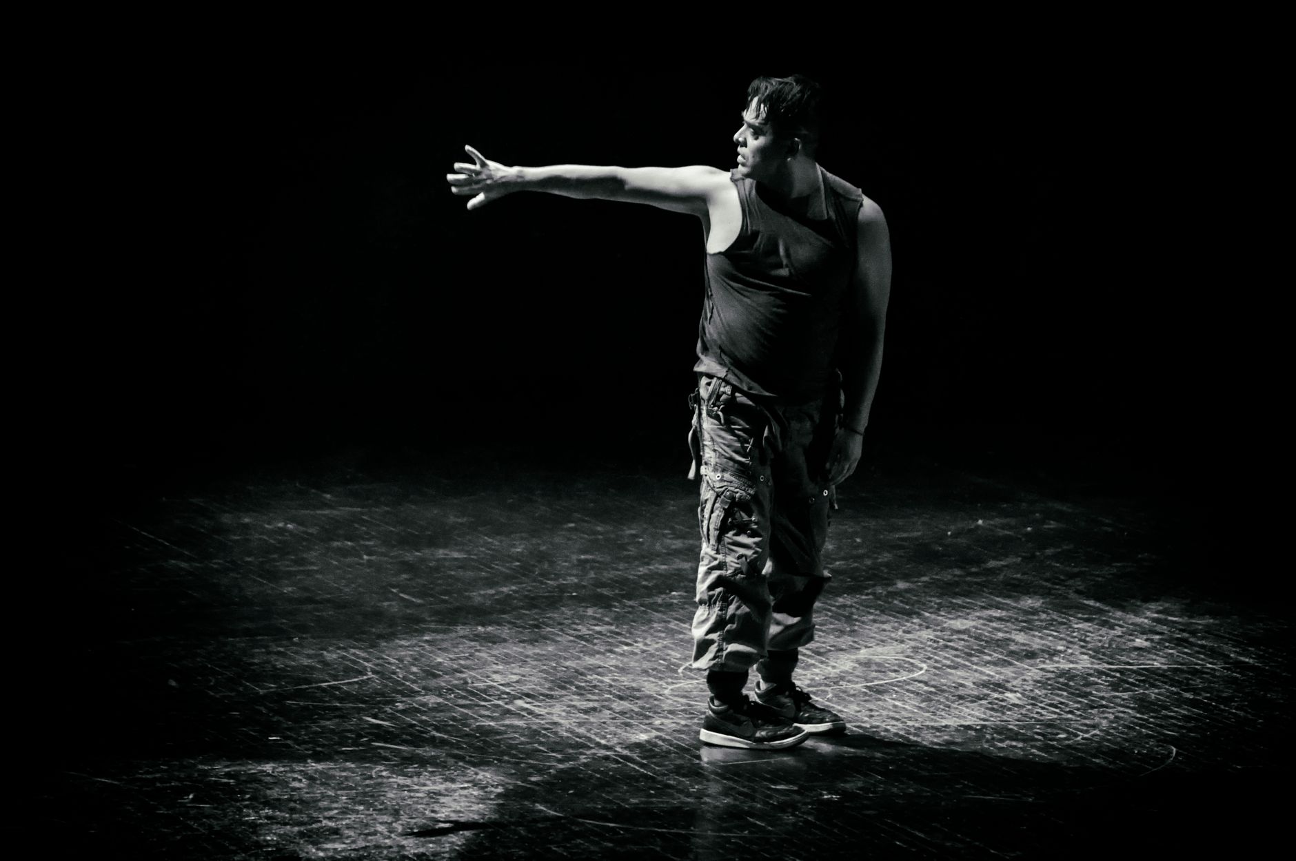 A performer standing under a single spotlight on a darkened stage