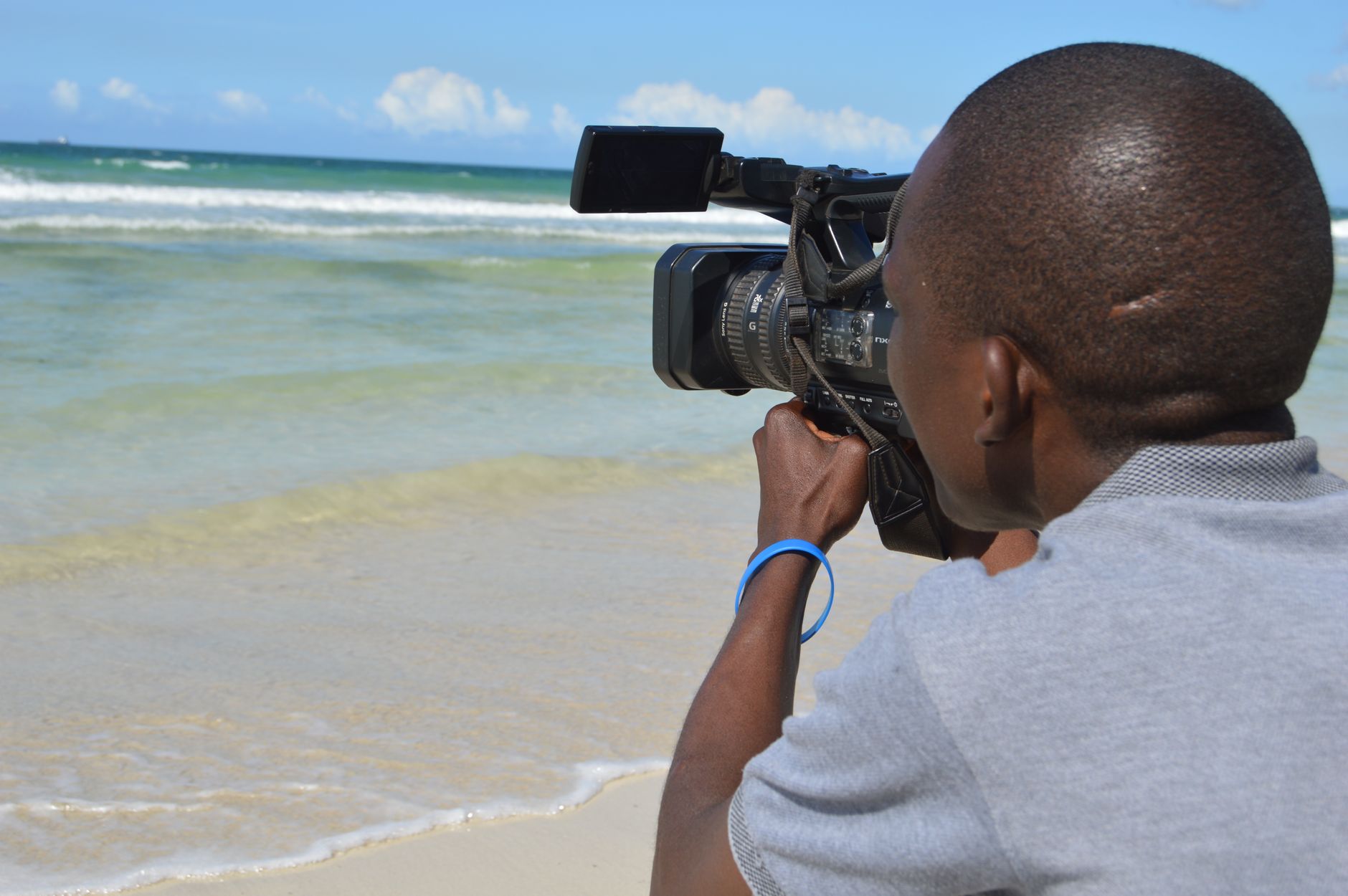 Person holding an underwater camera while observing ocean wildlife from a boat