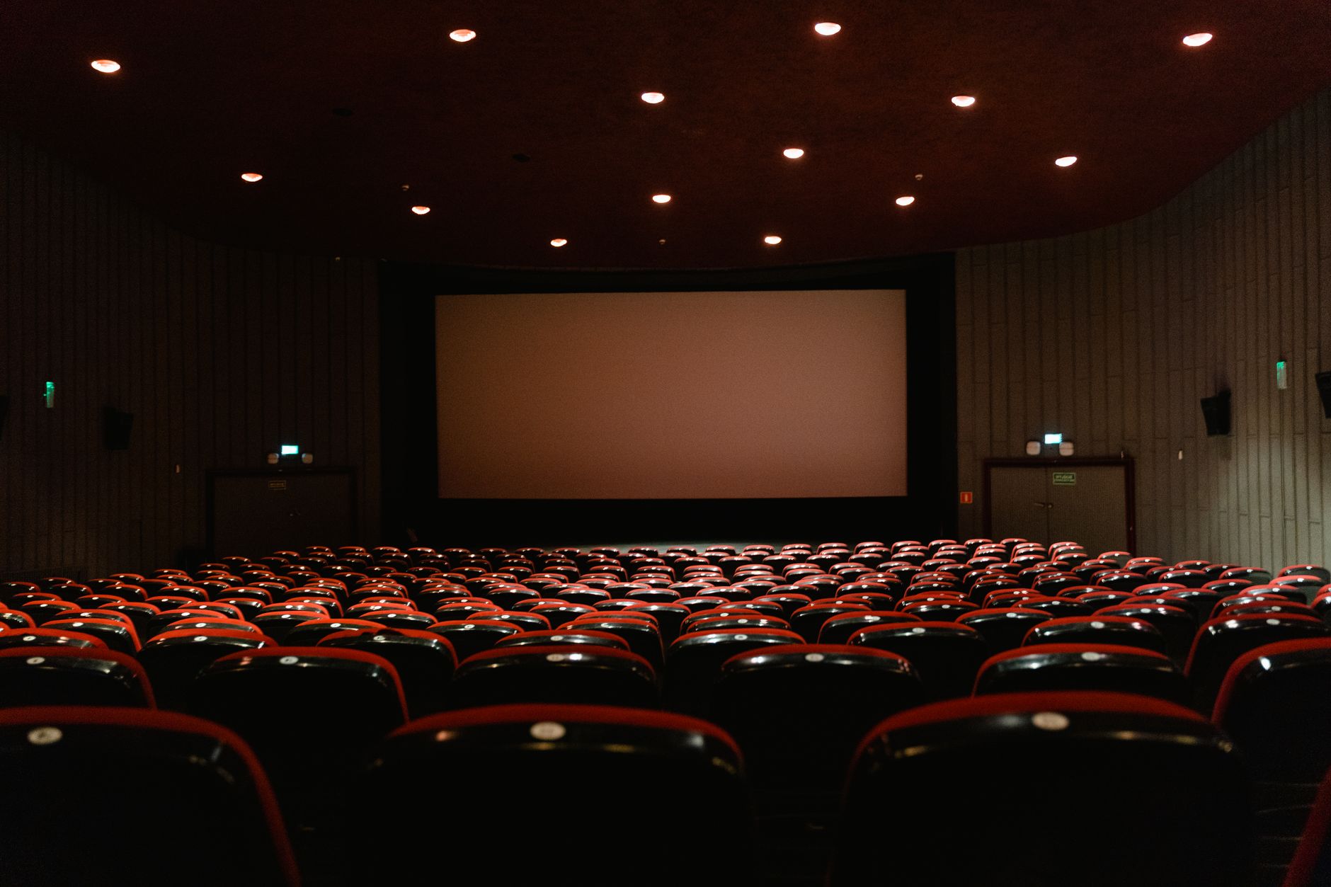Empty cinema seats facing a lit screen in a classic movie theater