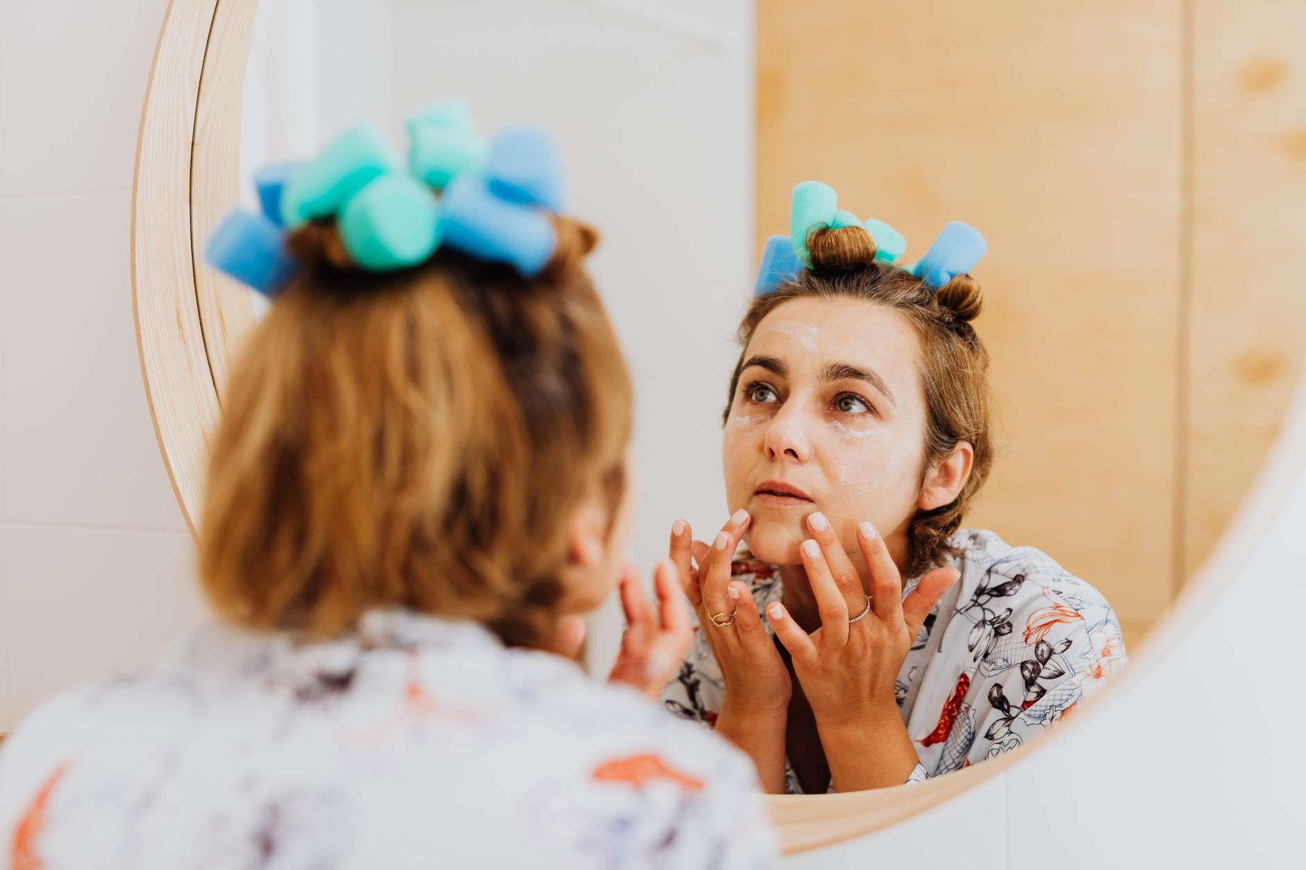 Person examining their hairline in a bathroom mirror