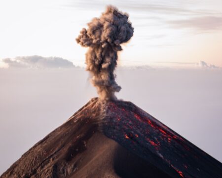 Thick ash cloud rising from a large volcanic eruption against a dark sky