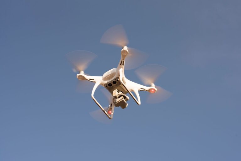 Small FPV drone in flight over open terrain representing autonomous strike drone technology