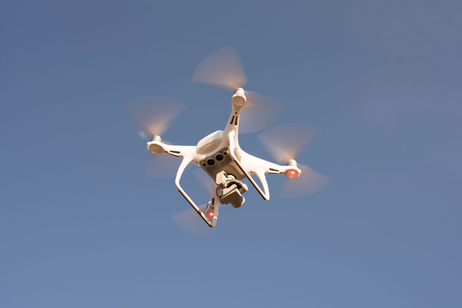 Small FPV drone in flight over open terrain representing autonomous strike drone technology