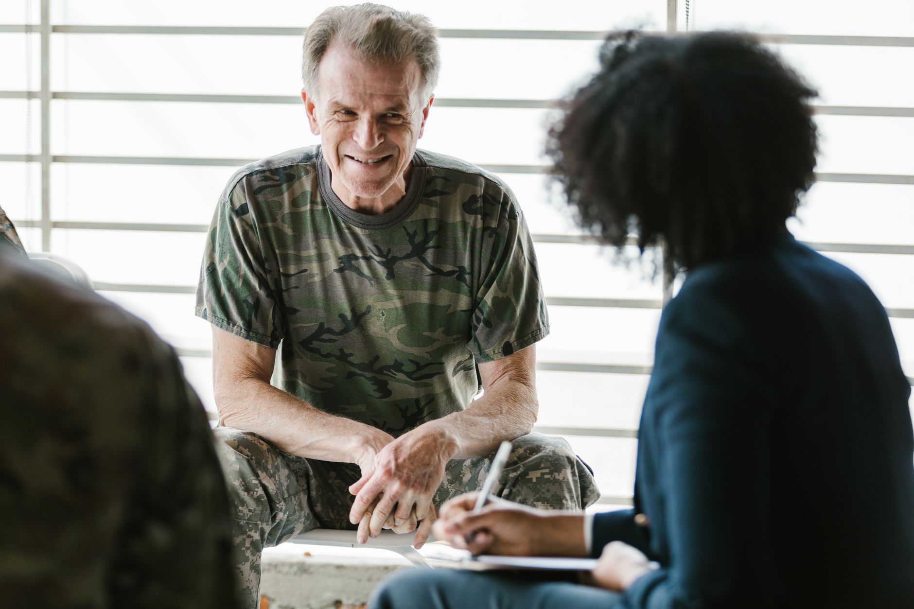 Military veteran in a clinical setting discussing treatment options with a healthcare provider